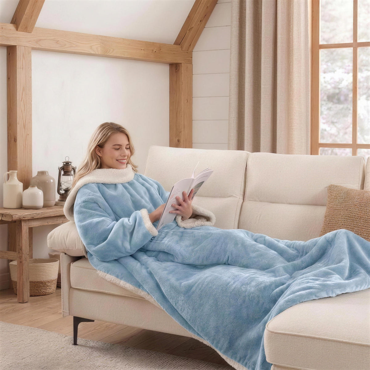 Woman reading on a farmhouse sofa in a light blue Kokoon heated blanket